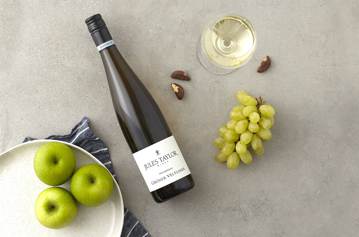 Bottle of Jules Taylor Gruner Veltliner with apples, grapes and brazil nuts