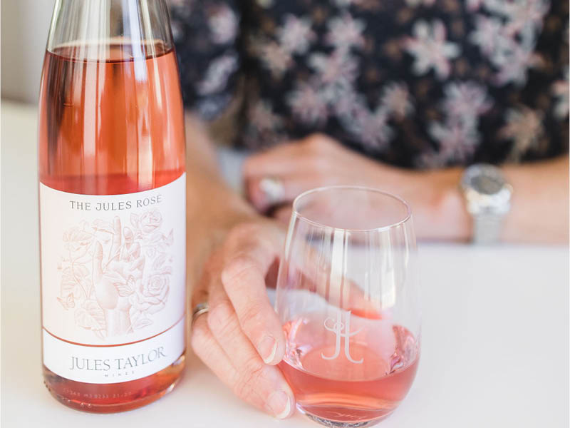 A bottle and hand holding a glass of The Jules Rosé