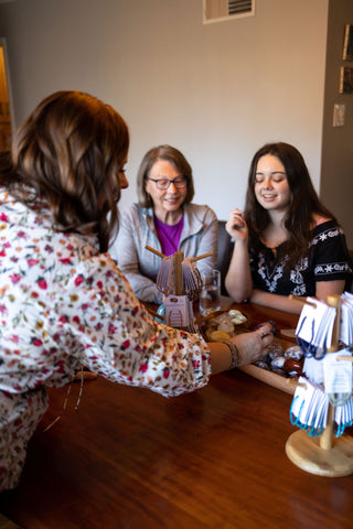 three women shop for crystals at a dining room table during an in-home private workshop