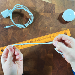 women's hands hold a length of string over an orange ruler