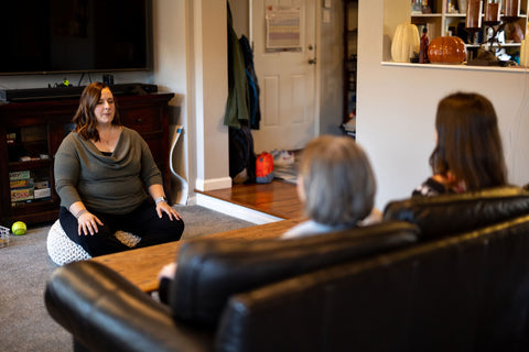 three women sit in a living room meditating
