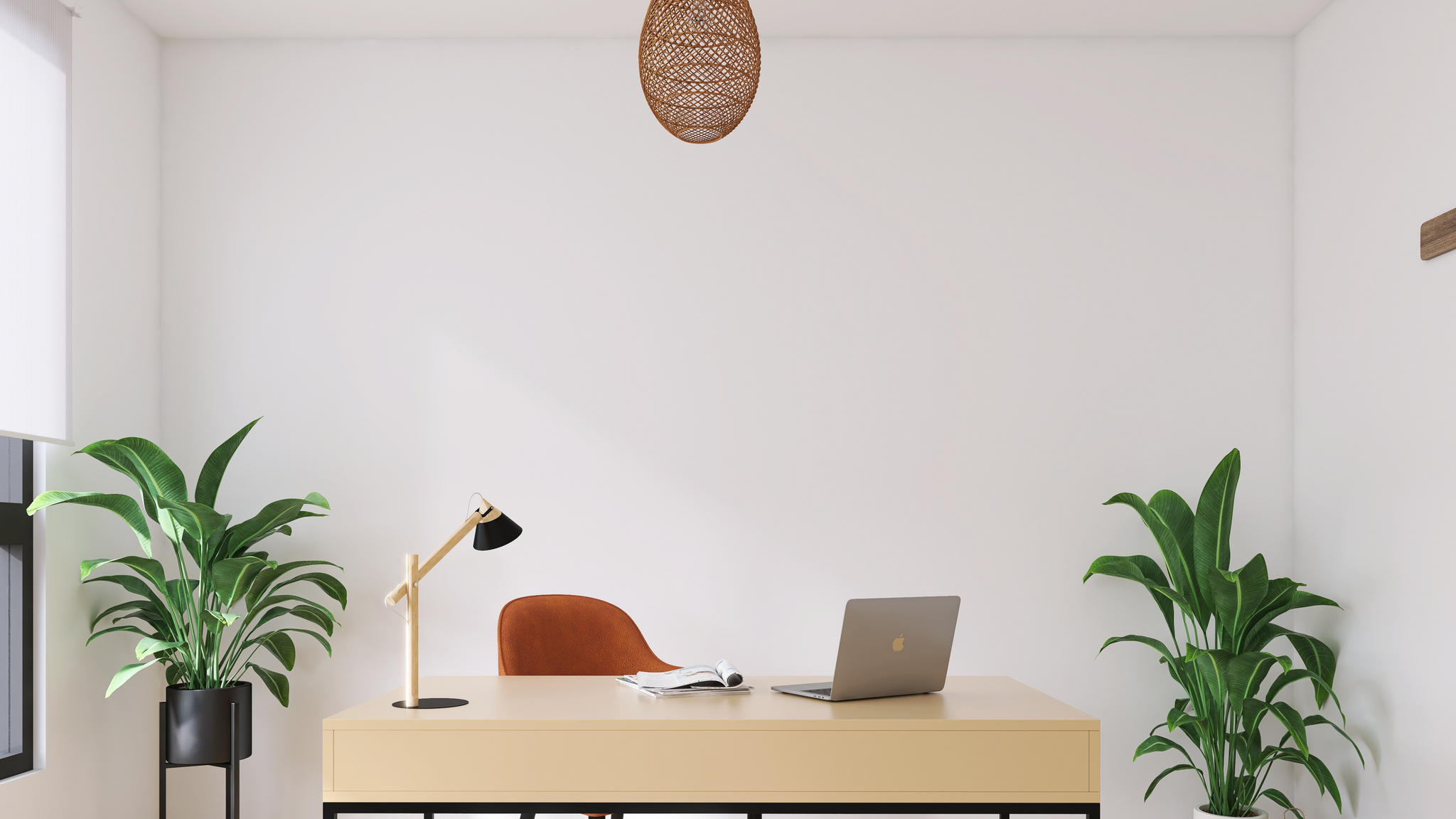 A white office with a light brown laptop desk surrounded by plants. A red chair and black table lamp