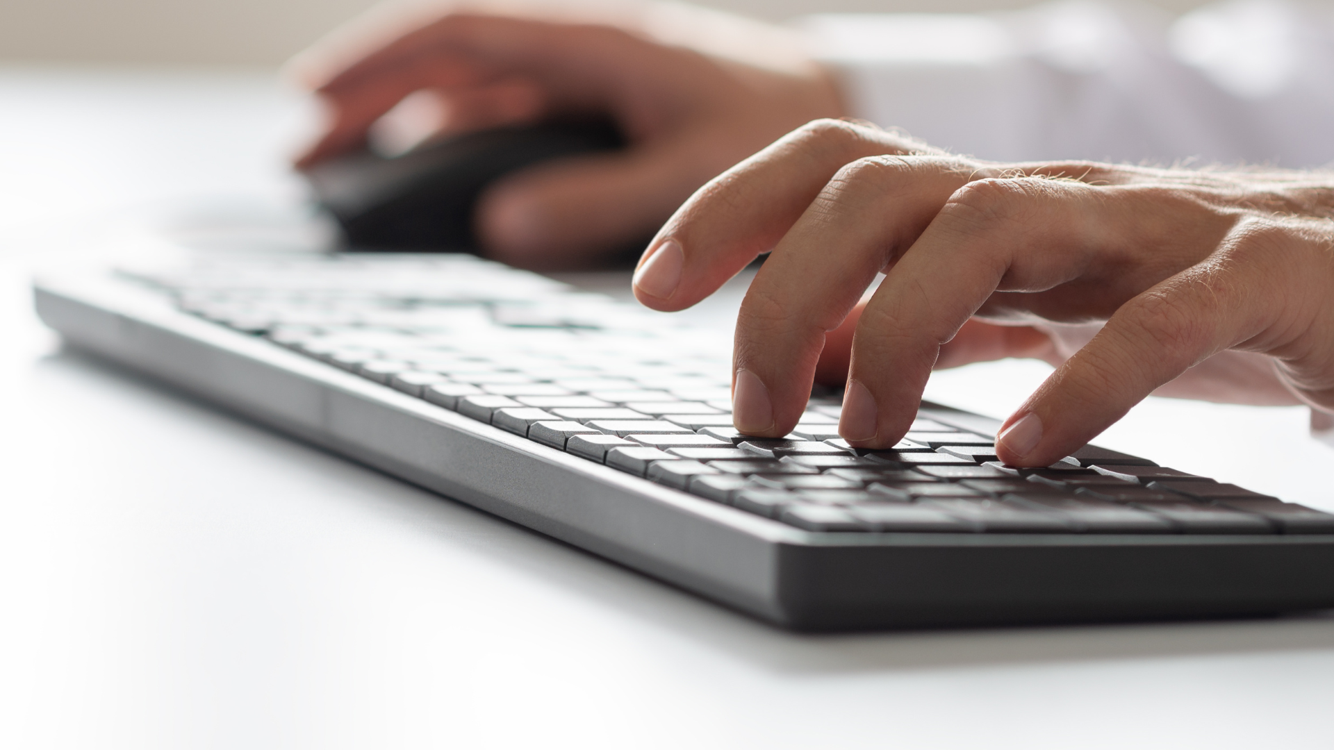 Close up of hands typing on a keyboard and using a computer mouse
