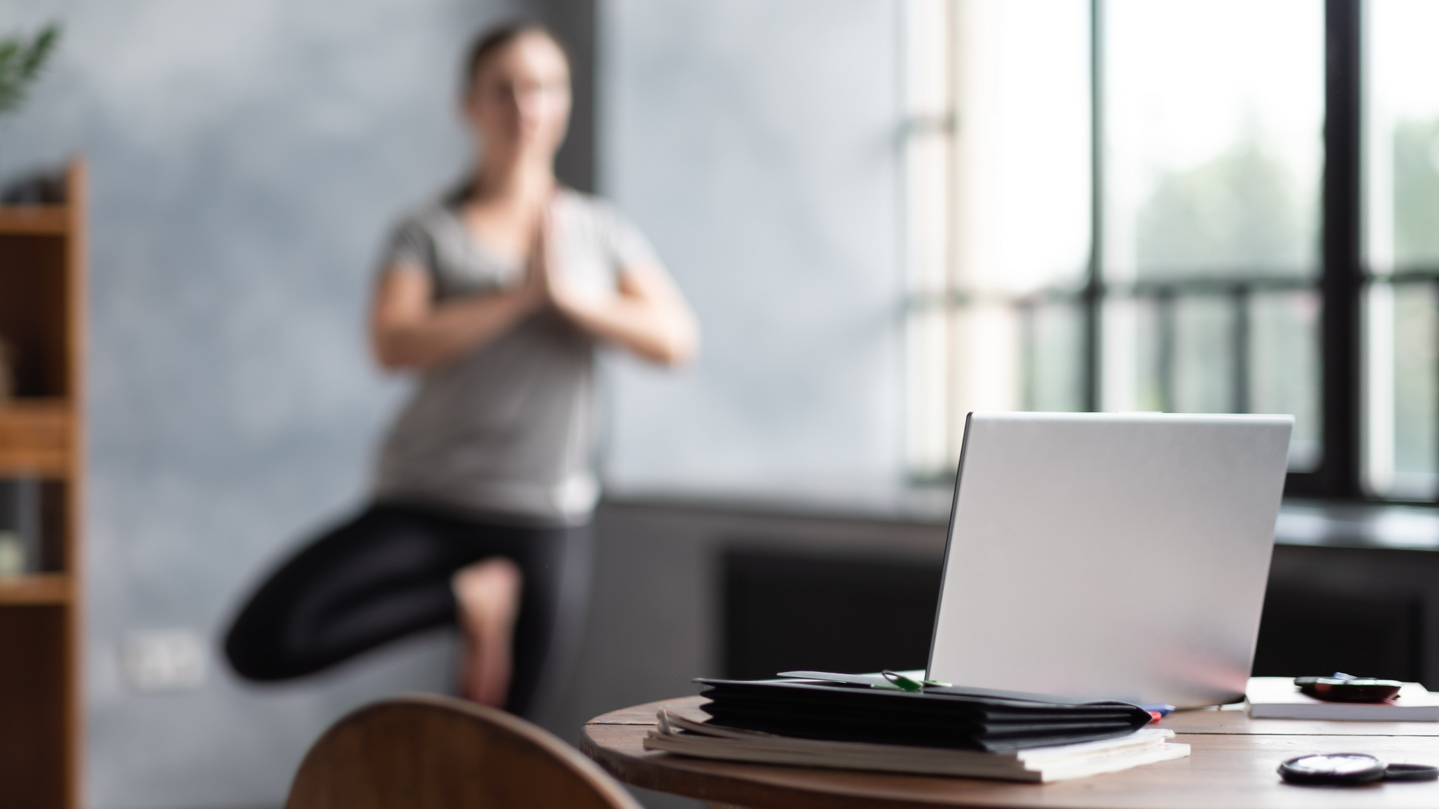 Photo of a woman doing a yoga pose in front of laptop