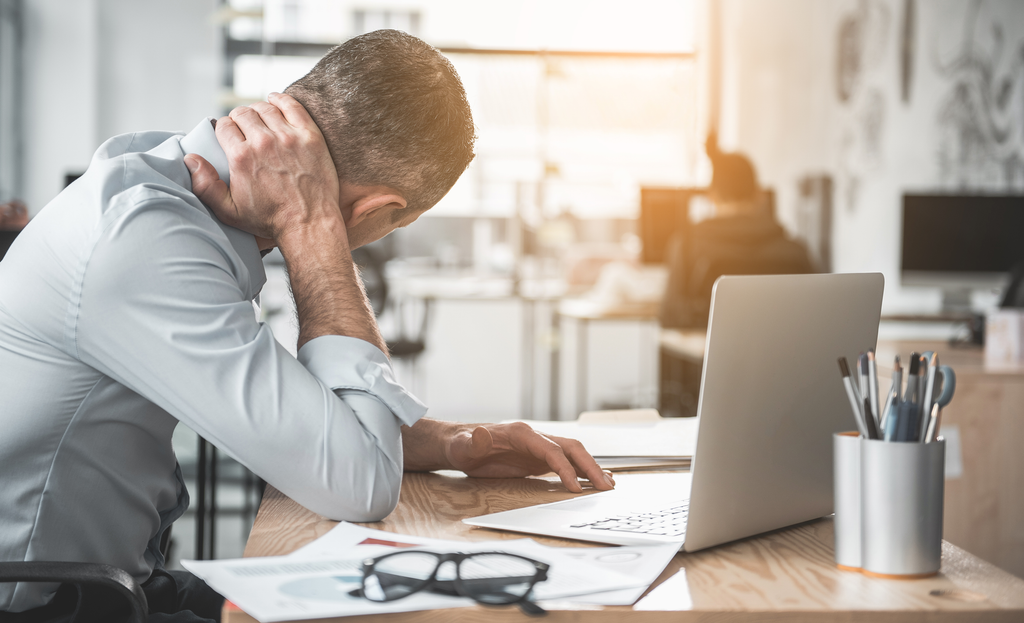 Man at desk clutching neck as if in pain