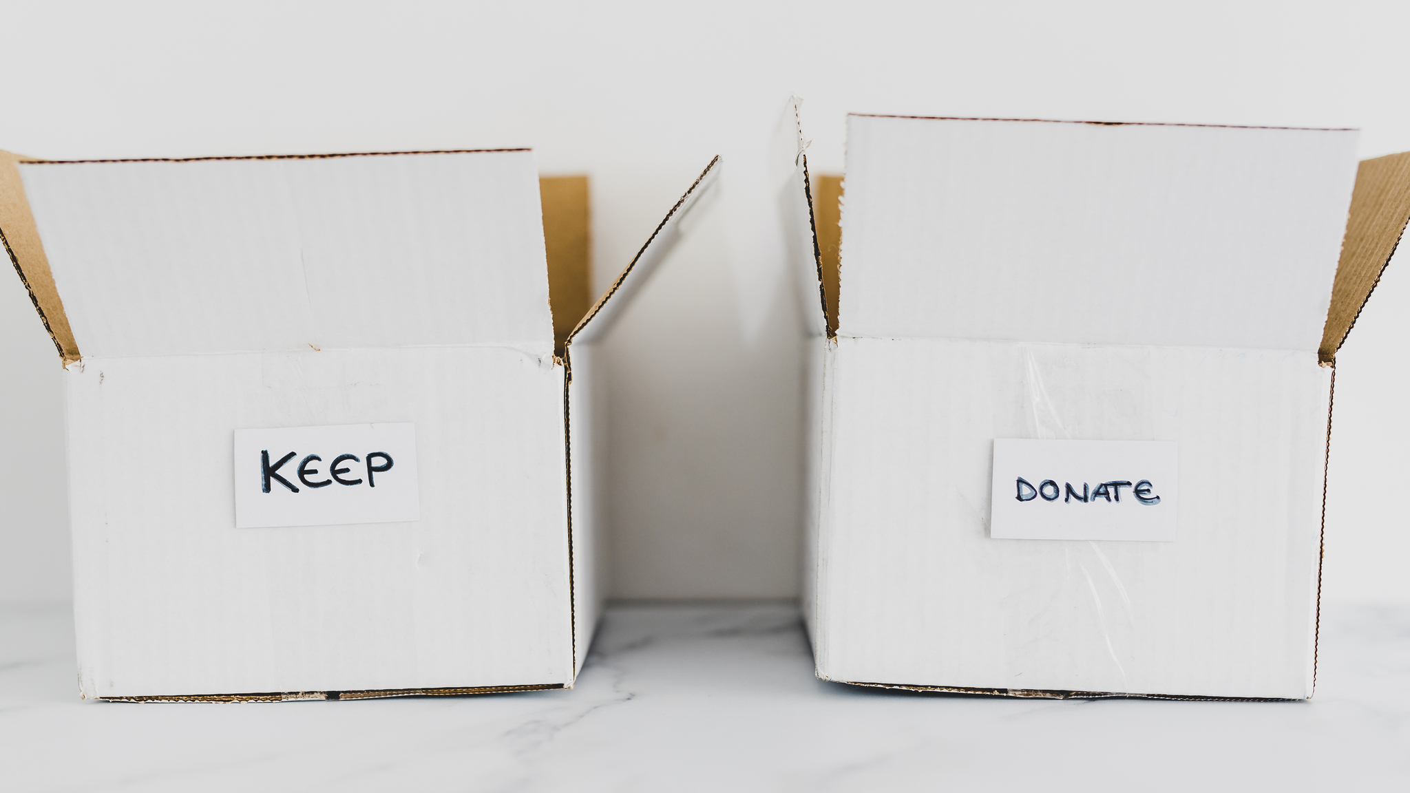 2 white cardboard boxes, one labeled "keep" and the other labeled "donate"