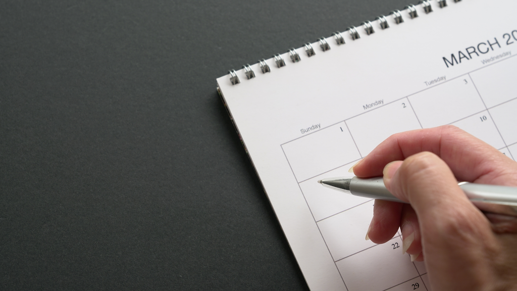 photo of a hand writing on a calendar