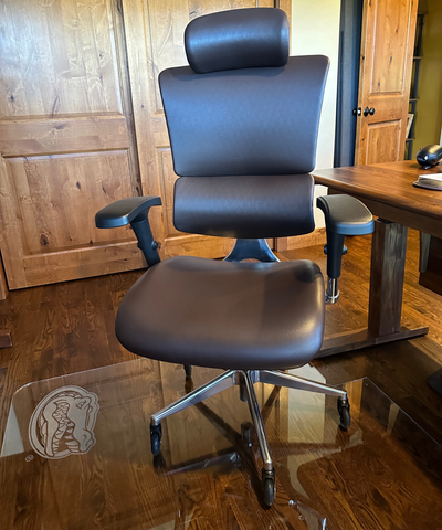A brown leather ergonomic office chair on an etched Glass Office Chair Mat with a Gator logo