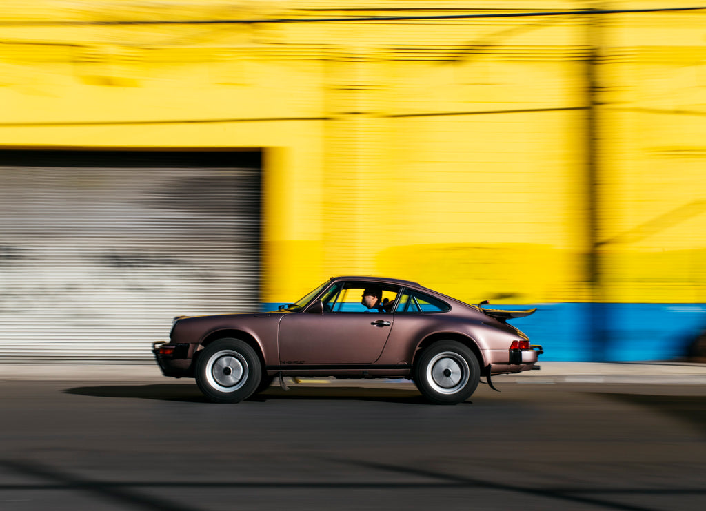 Cassis Red Metallic Porsche 911 Safari panning by yellow wall