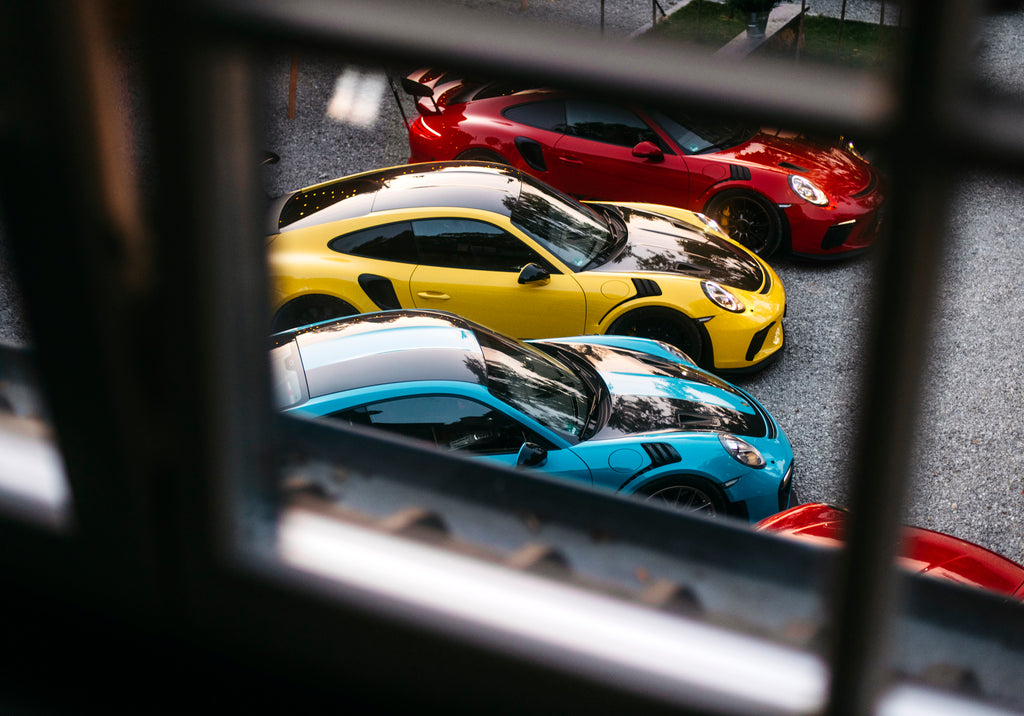 Through a window view of Yellow GT3 RS, Red Porsche 911 GT3 RS, and Miami Blue Porsche 911 GT2 RS in Belgium