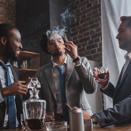 Three men smoking cigars in suits and drinking whisky