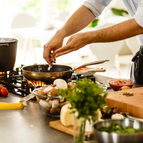 Person cooking in their kitchen with a frying pan