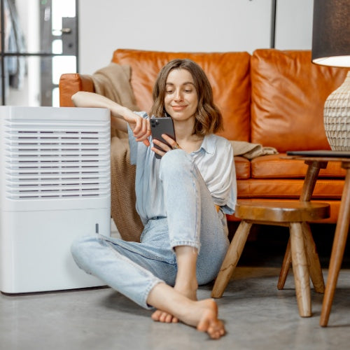 Woman sitting next to an air purifier in her living room