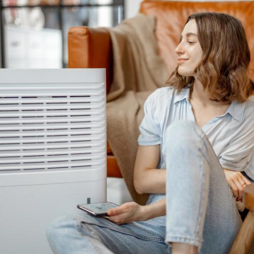 Woman sitting on floor in living room looking at her air purifier 