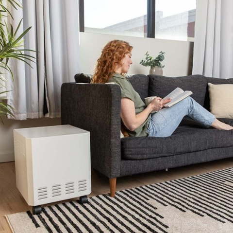 Woman reading comfortably in her living room with an EnviroKlenz Mobile Air System, showcasing the effectiveness of EnviroKlenz air purifiers in a home setting