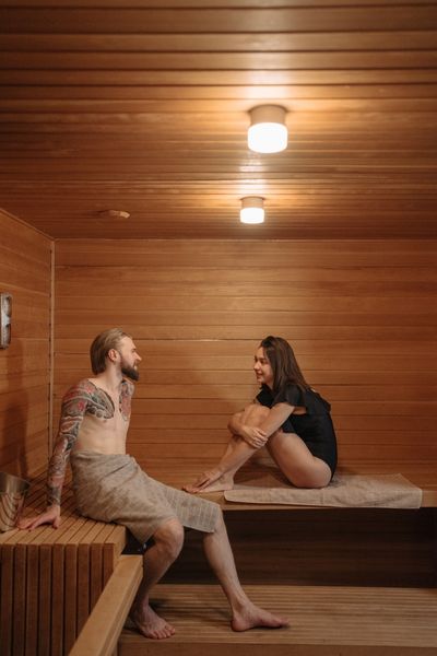 Woman and man sitting in a sauna with towels