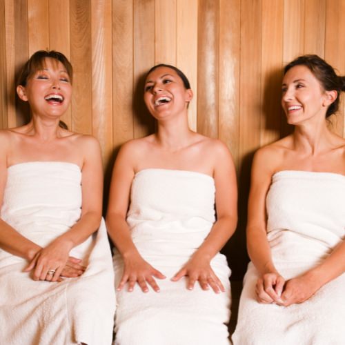 Three women sitting in a sauna laughing