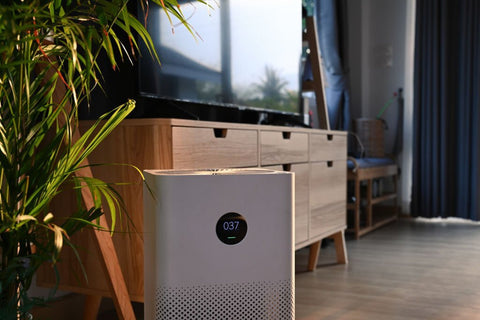 air purifier allergies sitting in front of a wooden credenza and window