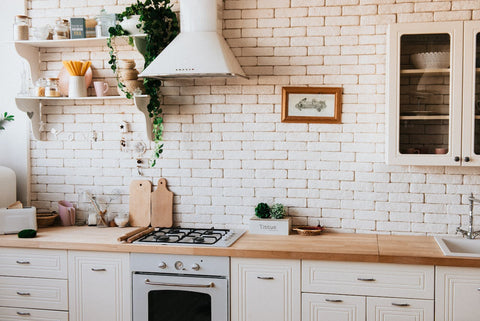Modern home kitchen interior with a clean design, featuring an air purifier on the countertop, white brick backsplash, and natural wood cabinets, creating a healthy cooking environment.