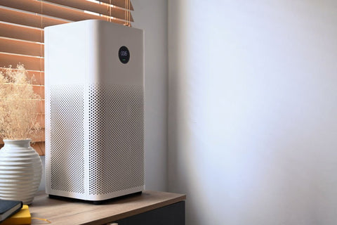 best air purifier for allergies - white purifier sitting on wood desk by window