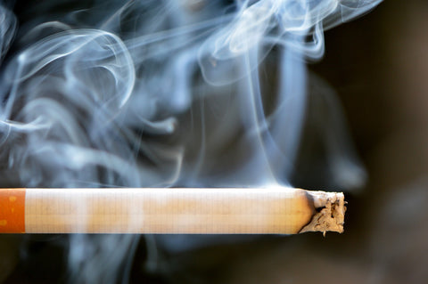 Close-up of a smoking cigarette, underscoring the importance of having an air purifier to reduce smoke exposure.