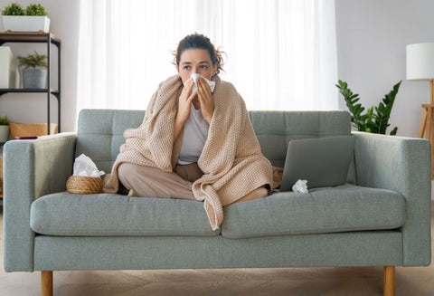 do air purifiers help with illness - with woman on couch, blowing her nose
