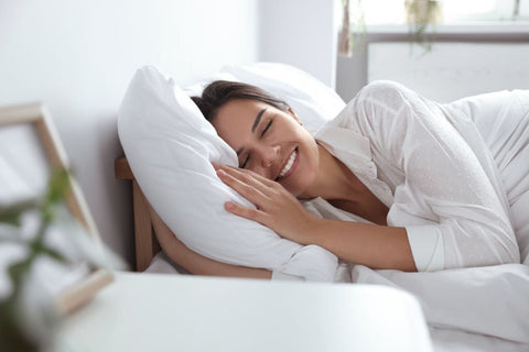 do air purifiers help with sleep - woman with her eyes closed smiling in bed