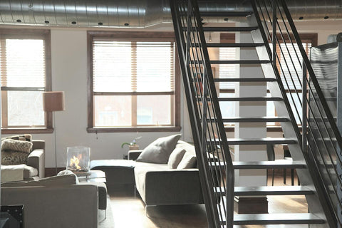 Stylish loft living space with an open floor plan, featuring a modern staircase, cozy sofas, and a fireplace, well-suited for an air cleaner to maintain a fresh and healthy environment.