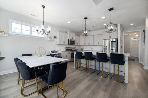 Contemporary open floor plan featuring a kitchen and dining area with marble table, velvet bar chairs, and elegant lighting—ideal for a room air purifier to enhance air quality