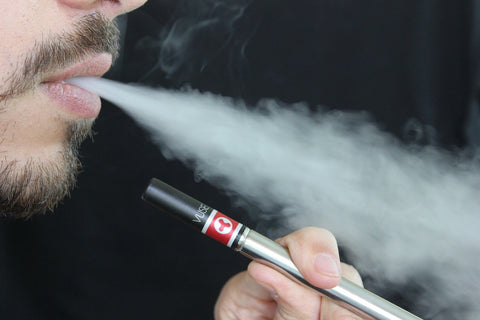 Man exhaling vapor from an e-cigarette, illustrating the use of a vape air purifier to clean indoor air.