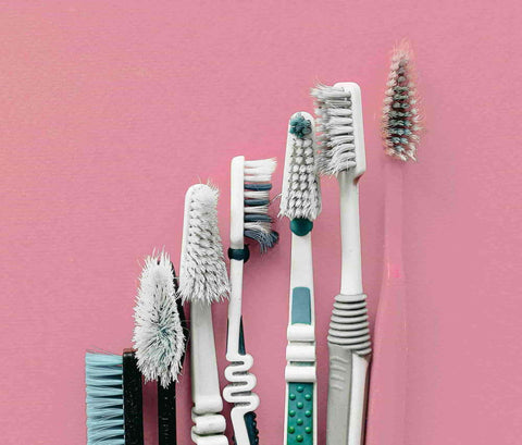 7 toothbrushes with split bristles in the pink background.