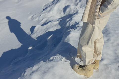 The shadow of musician Quinn Christopherson's pants and boots reflected in the snow.