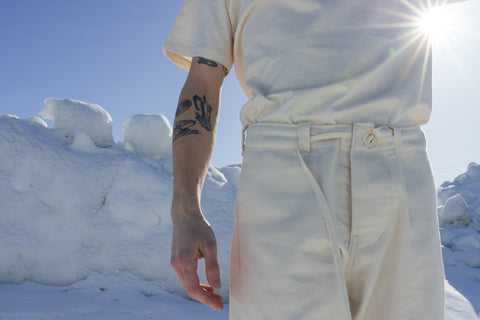 Musician Quinn Christopherson in an ALL WE REMEMBER undyed organic cotton t-shirt and twill pants.