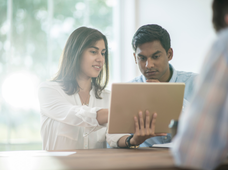 Two people proofing translation on laptop