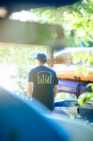 Standing by a canoe in the Keep Bigfoot Hidden Tee