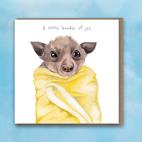 Greeting card with painted baby bat wrapped in yellow blanket and words A little bundle of joy