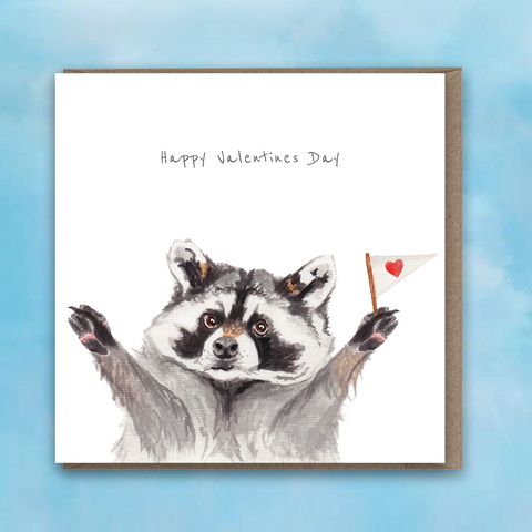 Greeting card featuring a painted raccoon with a small heart flag and text saying Happy Valentines Day