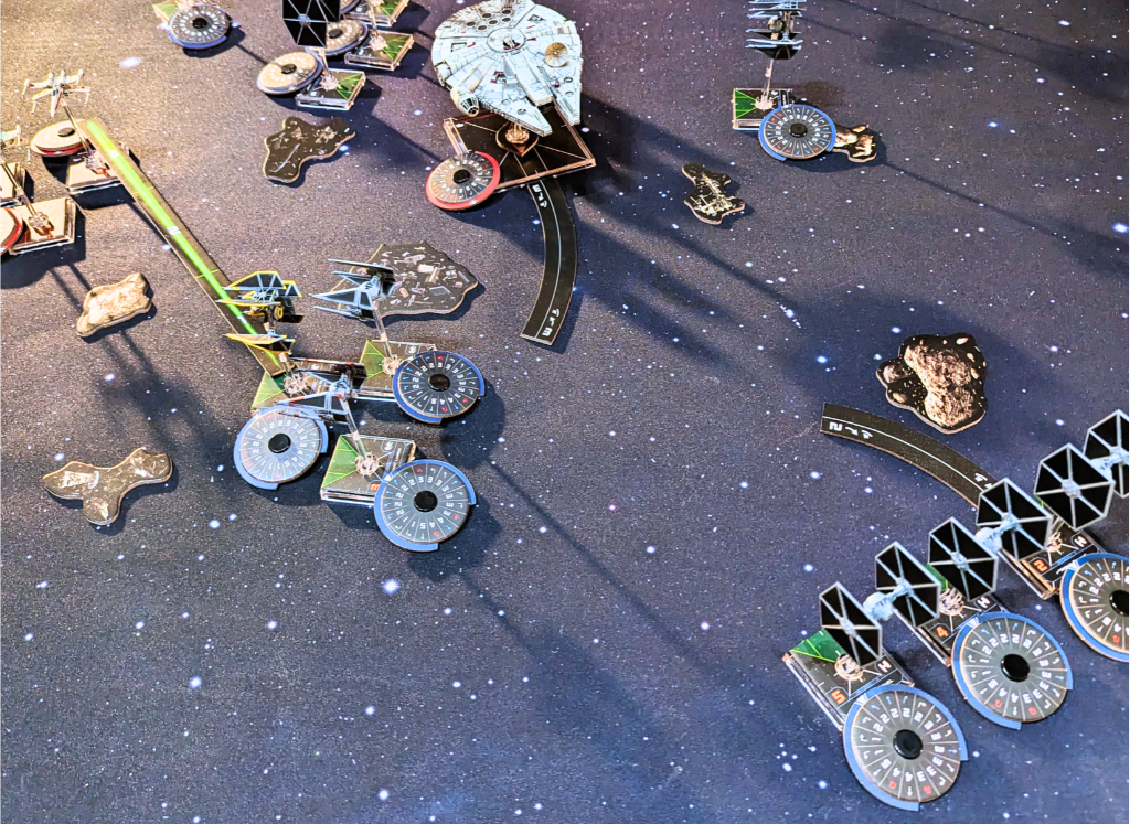 Tiny Star Wars ships arrayed in a battle across a large, starry playmat