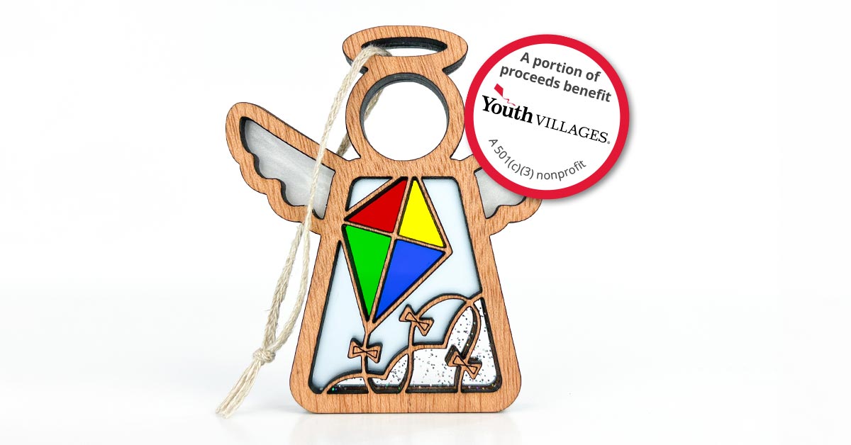 A Mother’s Angels® ornament from Forged Flare® with a kite motif, handcrafted with elements resembling stained glass. The ornament features a tag stating that a portion of proceeds benefits Youth Villages in Memphis, Tennessee, supporting their mission as a 501(c)(3) nonprofit organization. By purchasing, customers donate to charity and contribute to the community.