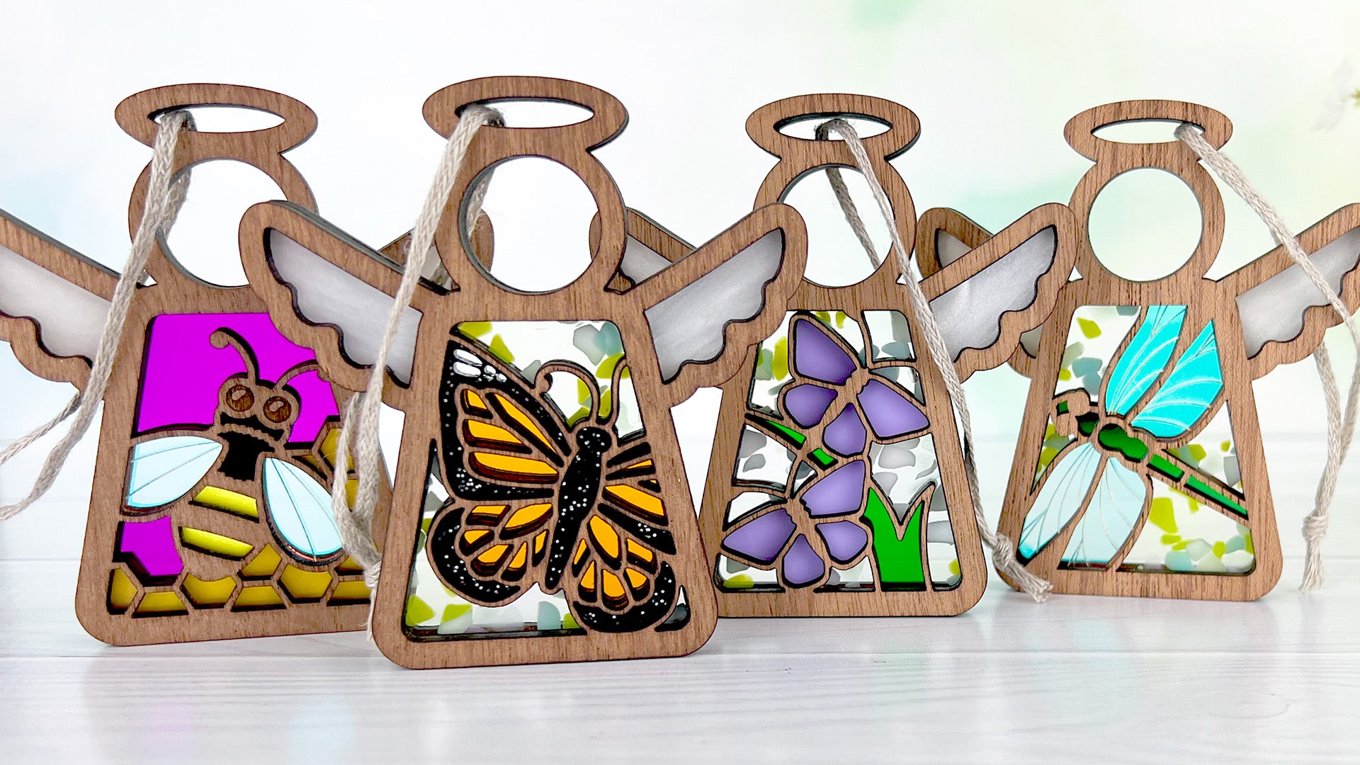 Mother’s Angels® Honey Bee ornament, Monarch Butterfly ornamenty, Playful Purple Butterflies ornament and Dragonfly ornament lined up in a row.