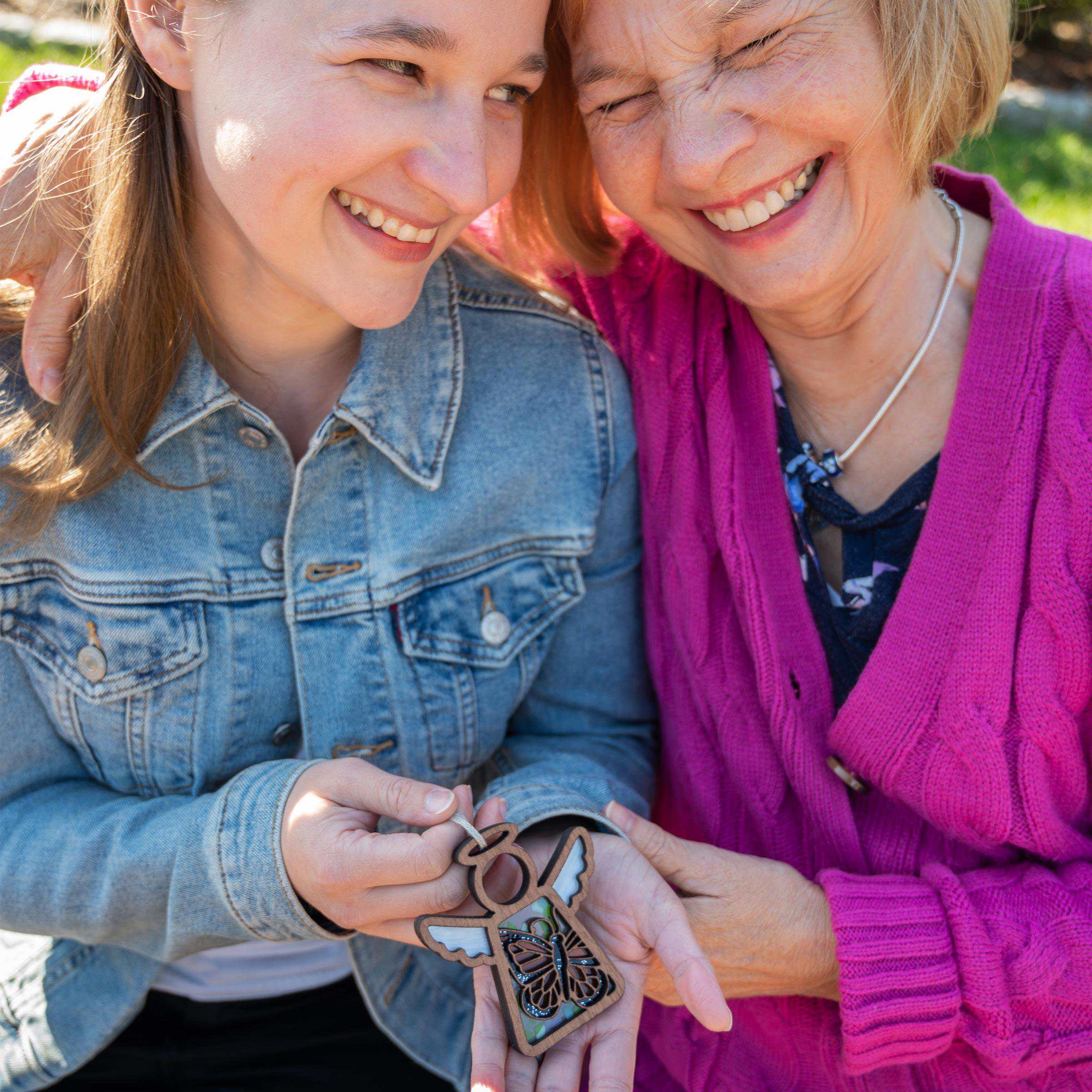 A mother and daughter giggling over a monarch butterfly angel figurine gift
