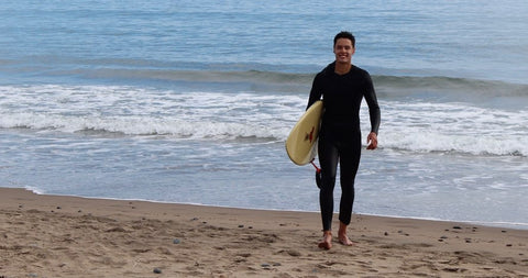 Liam s'approchant du rivage avec une planche de surf à la main