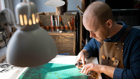 Kyle MacPhee coupe du cuir sur son poste de travail chez Phee's Original Goods