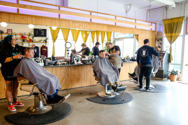 Une équipe de barbiers chez Lucky Cat Barbershop donnant des coupes de cheveux