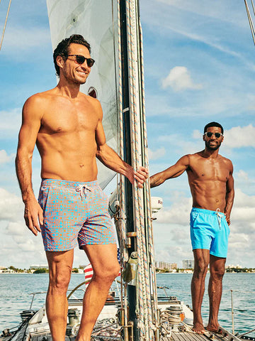 Two men wearing Fair Harbor swim trunks on a sailboat