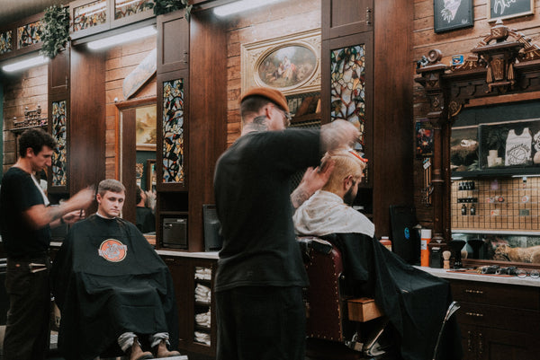 Un coiffeur chez Oddfellows Barbershop donnant une coupe de cheveux
