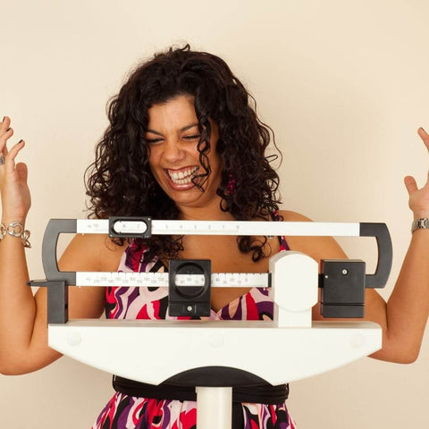 woman on a scale smiling and checking her weight loss