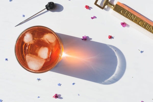 Letter vitamins: An overhead view of an iced drink focusing sunlight to a point in the tall shadow of the glass. 