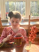 A girl weaves yarn on a cup.