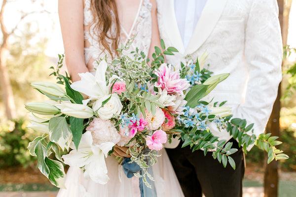 bride and groom holding green, pink, and blue bridal bouquet for spring wedding